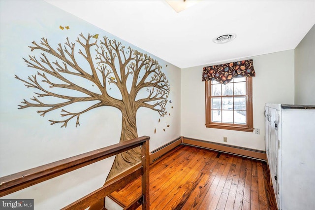 spare room featuring baseboard heating and hardwood / wood-style floors