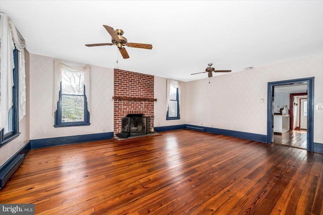 unfurnished living room with dark wood-type flooring, a baseboard radiator, a fireplace, and ceiling fan