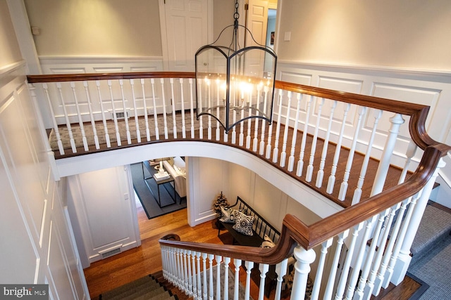 staircase with hardwood / wood-style flooring and a notable chandelier