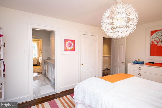 bedroom featuring connected bathroom, an inviting chandelier, and dark hardwood / wood-style flooring