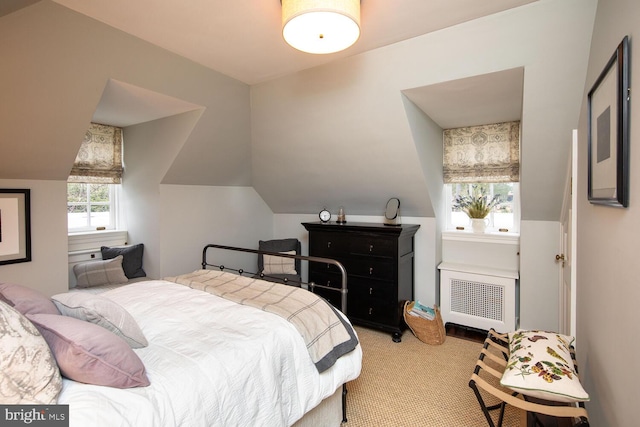 carpeted bedroom featuring radiator heating unit and vaulted ceiling