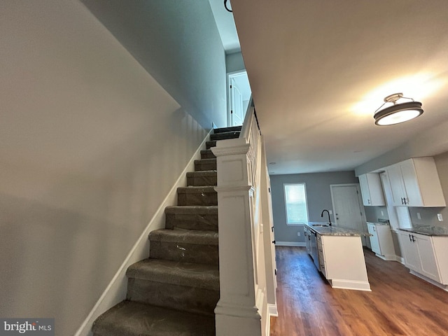 staircase with sink and hardwood / wood-style flooring