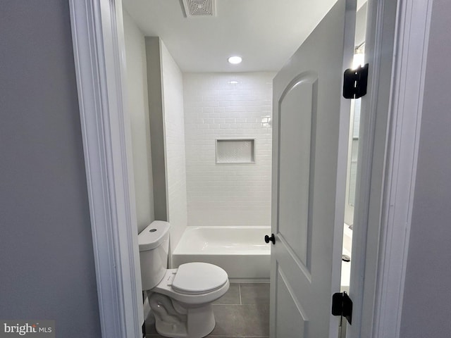 bathroom featuring tiled shower / bath combo, toilet, and tile patterned flooring