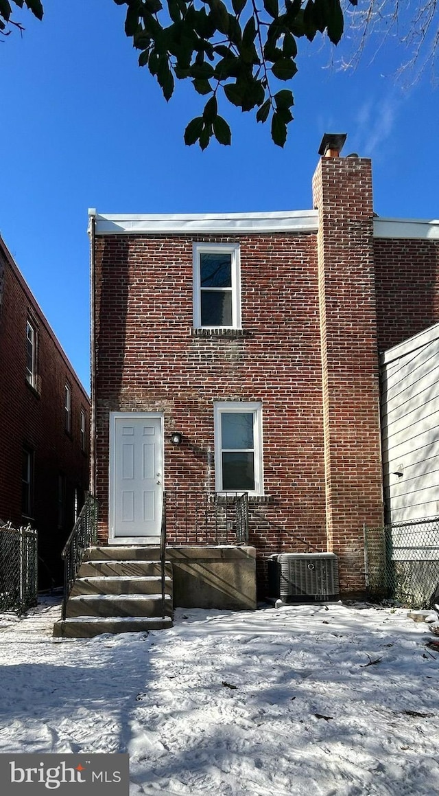 snow covered rear of property with central AC