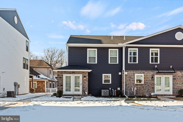 snow covered house featuring cooling unit and french doors