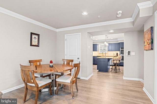 dining area featuring sink, crown molding, and light hardwood / wood-style floors