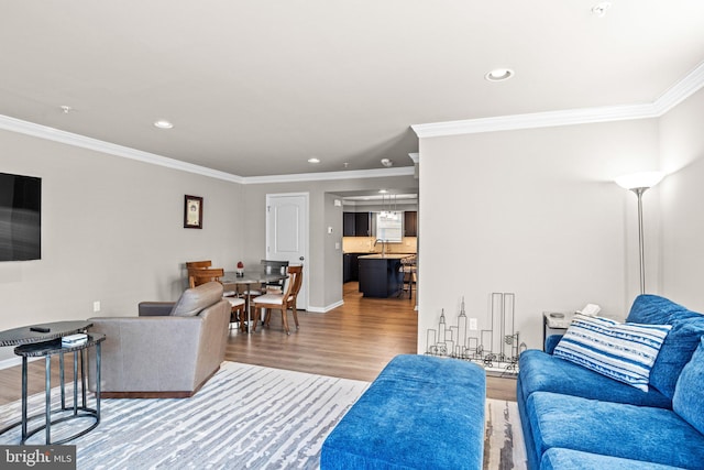 living room featuring ornamental molding, sink, and hardwood / wood-style floors