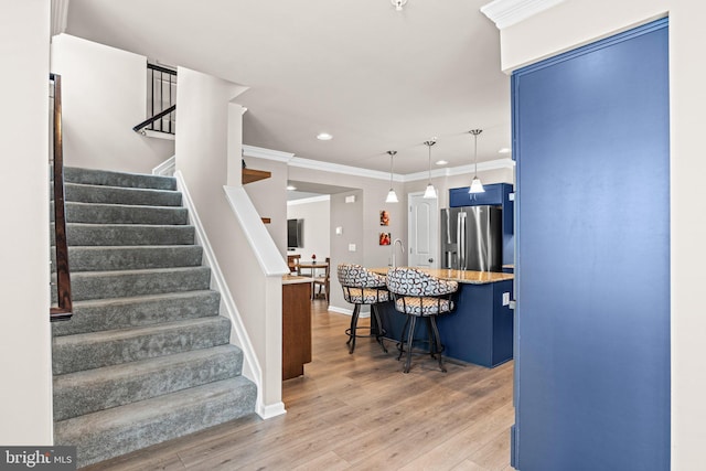 staircase featuring hardwood / wood-style floors, ornamental molding, and sink