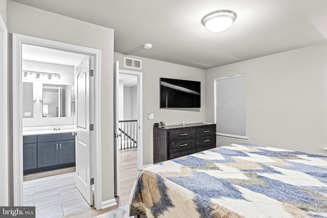 bedroom with ensuite bathroom, sink, and light wood-type flooring