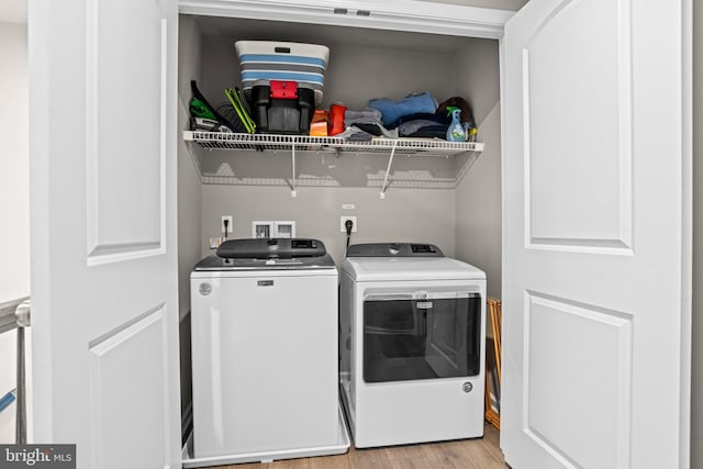 laundry area with washer and dryer and light hardwood / wood-style flooring