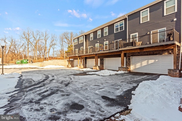 snow covered back of property with a garage