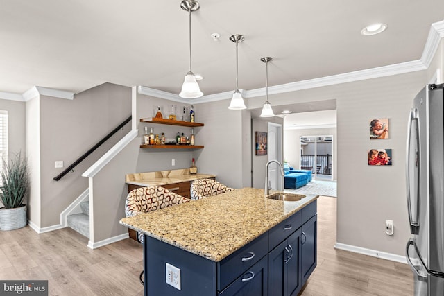 kitchen featuring sink, stainless steel fridge, blue cabinetry, a kitchen breakfast bar, and an island with sink