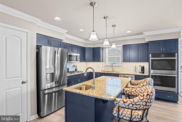 kitchen with light stone countertops, appliances with stainless steel finishes, sink, and a kitchen island with sink