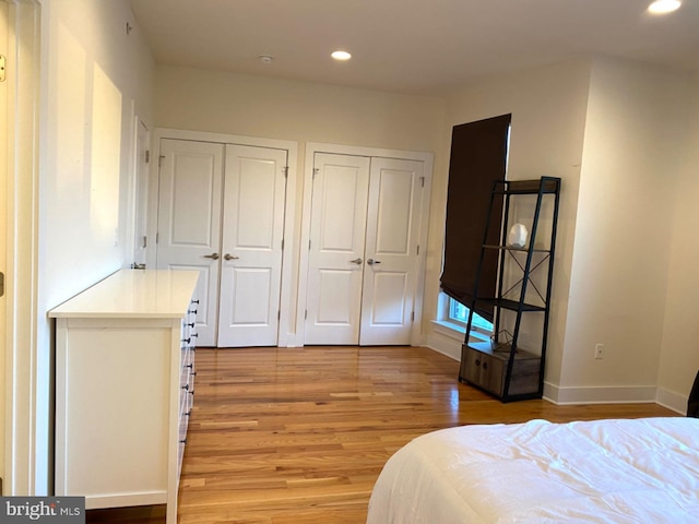 bedroom with light wood-type flooring and two closets