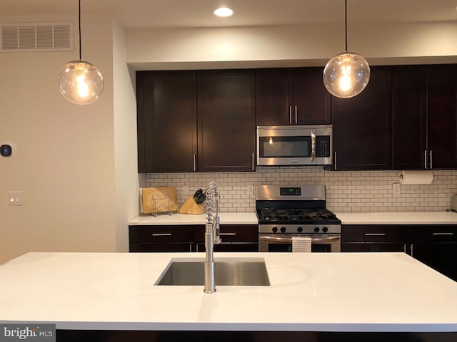 kitchen with tasteful backsplash, hanging light fixtures, sink, dark brown cabinetry, and stainless steel appliances