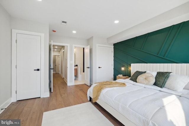 bedroom with hardwood / wood-style floors and ensuite bath