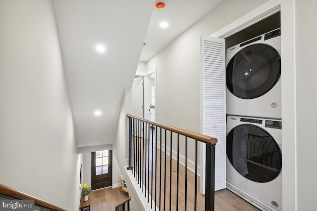 laundry area with stacked washer / drying machine and light wood-type flooring