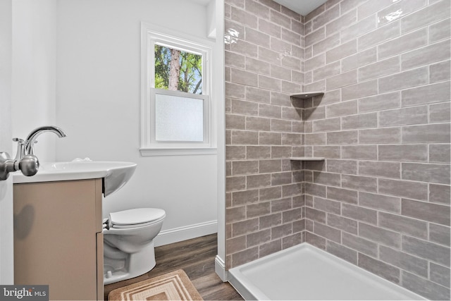 bathroom with vanity, wood-type flooring, toilet, and tiled shower