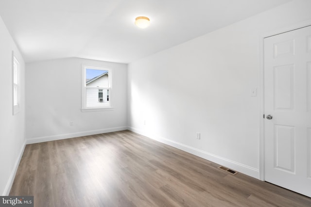 empty room featuring lofted ceiling and hardwood / wood-style flooring