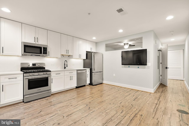 kitchen with light hardwood / wood-style floors, white cabinets, and stainless steel appliances