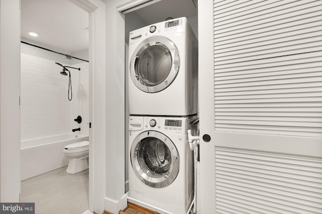 laundry room featuring stacked washer / drying machine and light tile patterned flooring