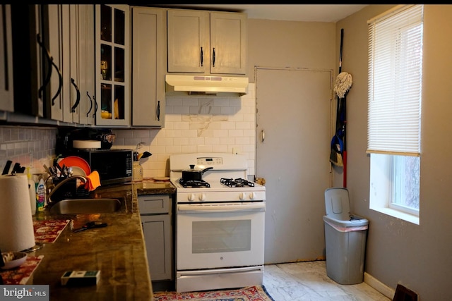 kitchen featuring backsplash, white gas range, sink, and gray cabinetry