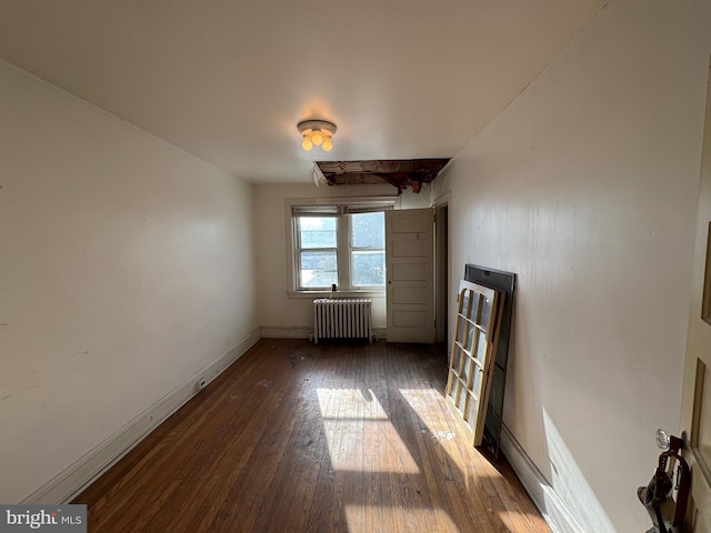 unfurnished room with dark hardwood / wood-style floors and radiator