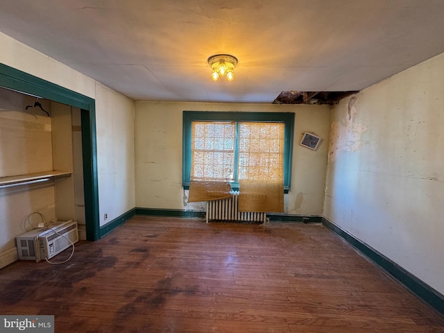 interior space with a wall mounted AC, radiator, and dark hardwood / wood-style flooring