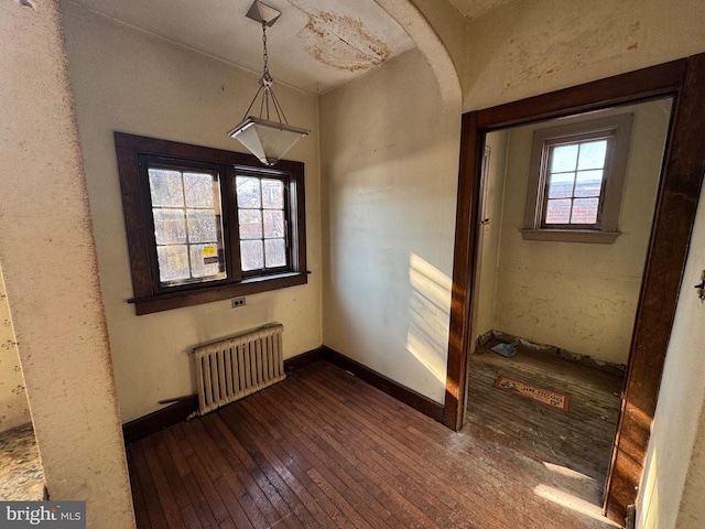 unfurnished dining area with radiator and dark hardwood / wood-style flooring