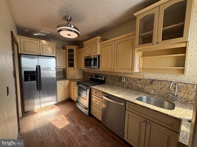 kitchen featuring light stone counters, sink, backsplash, and stainless steel appliances