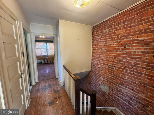 hall with dark wood-type flooring and brick wall