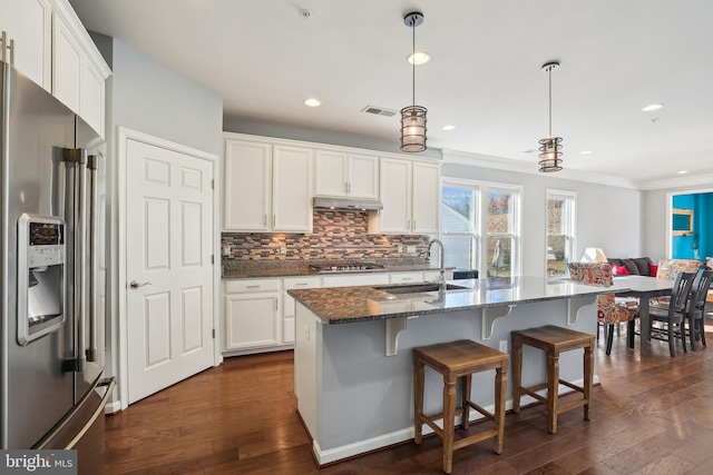 kitchen with sink, white cabinetry, a center island with sink, appliances with stainless steel finishes, and dark stone counters