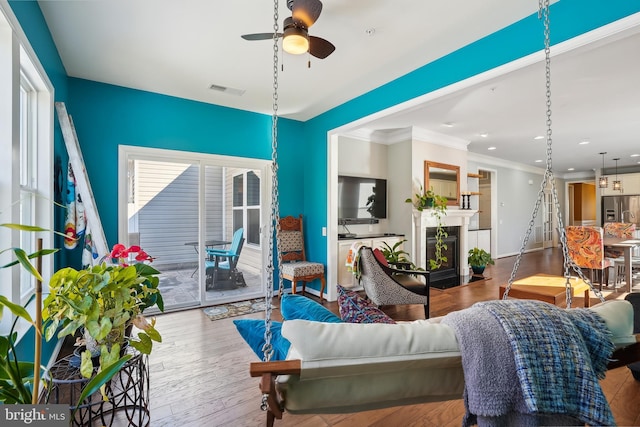 living room with ornamental molding, hardwood / wood-style floors, and ceiling fan