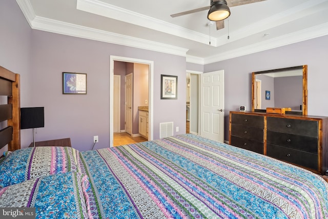 bedroom with a raised ceiling, ornamental molding, ceiling fan, and ensuite bath