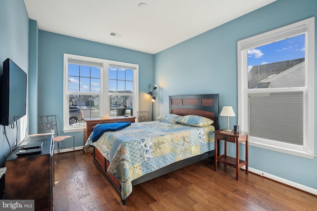 bedroom with multiple windows and dark hardwood / wood-style flooring