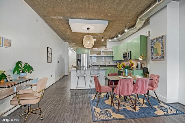 dining room with sink, rail lighting, and dark wood-type flooring