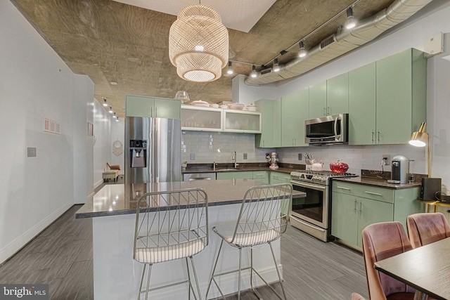 kitchen with decorative backsplash, sink, green cabinets, and stainless steel appliances