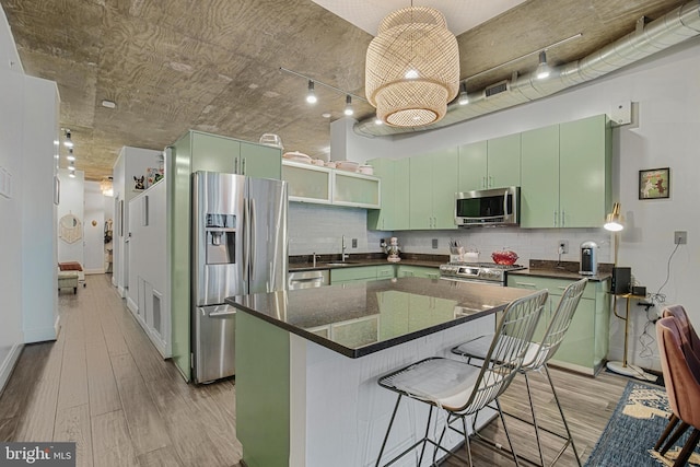 kitchen featuring tasteful backsplash, green cabinetry, sink, a breakfast bar, and stainless steel appliances