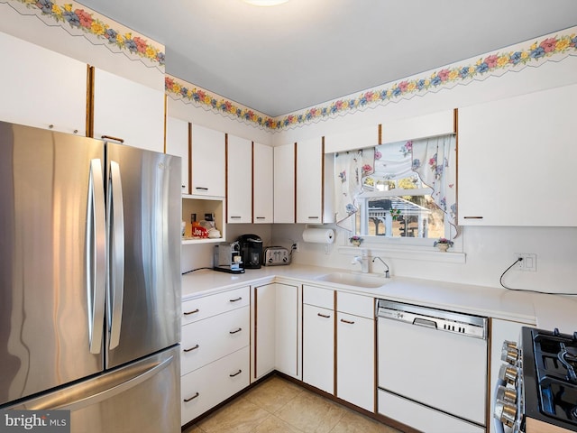 kitchen with white cabinetry, sink, light tile patterned floors, and stainless steel appliances