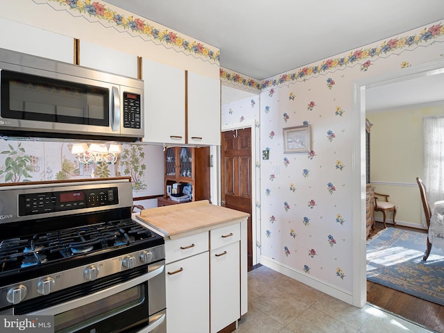 kitchen with white cabinetry, stainless steel appliances, and light tile patterned flooring