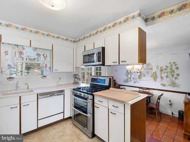 kitchen with white cabinetry, stainless steel appliances, sink, and light tile patterned floors