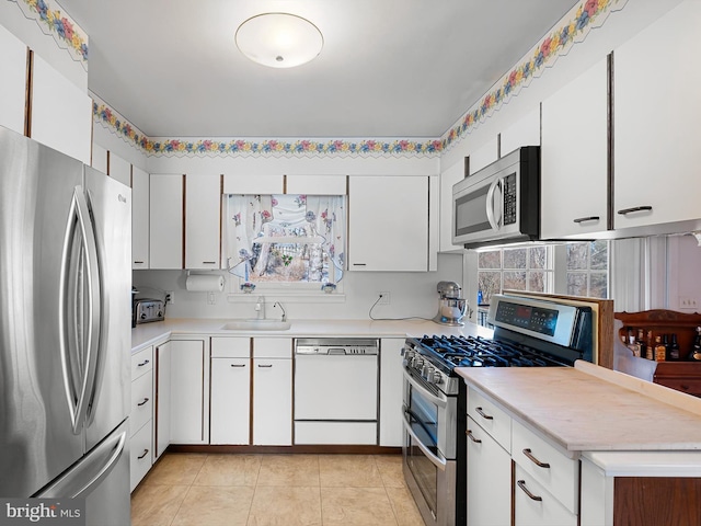 kitchen featuring light tile patterned floors, stainless steel appliances, sink, and white cabinets