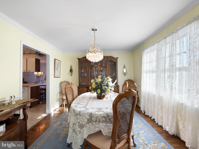 dining space with an inviting chandelier, crown molding, and dark wood-type flooring