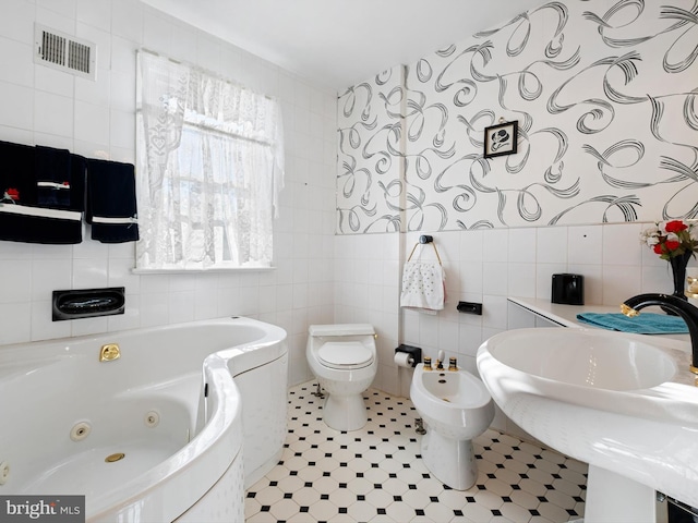 bathroom with a bathing tub, a bidet, tile walls, and toilet