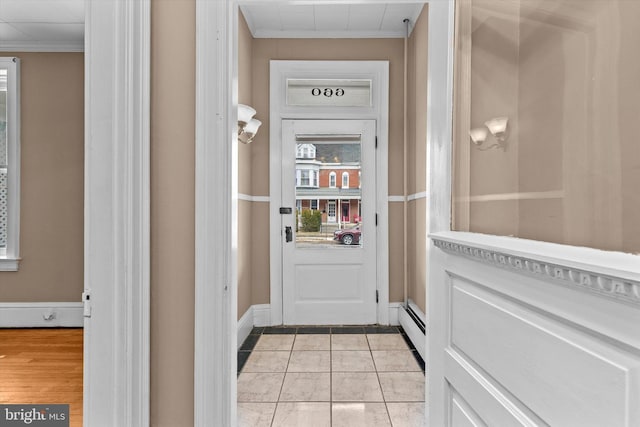 entryway featuring a baseboard radiator, light tile patterned floors, and crown molding