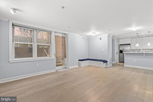 unfurnished living room with ornamental molding and light hardwood / wood-style floors