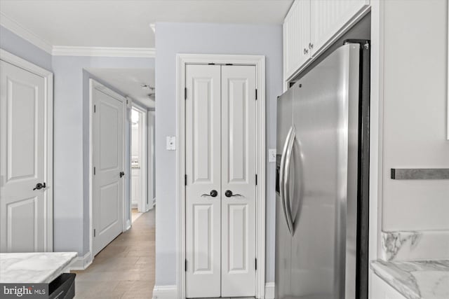 kitchen with stainless steel fridge with ice dispenser, white cabinetry, light stone counters, and crown molding