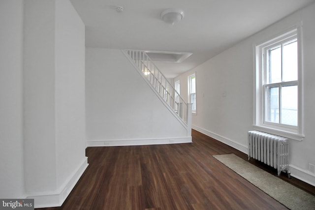 spare room featuring a healthy amount of sunlight, radiator, and dark hardwood / wood-style floors