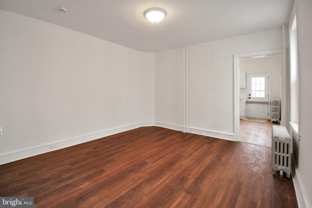 unfurnished room featuring radiator heating unit and dark wood-type flooring