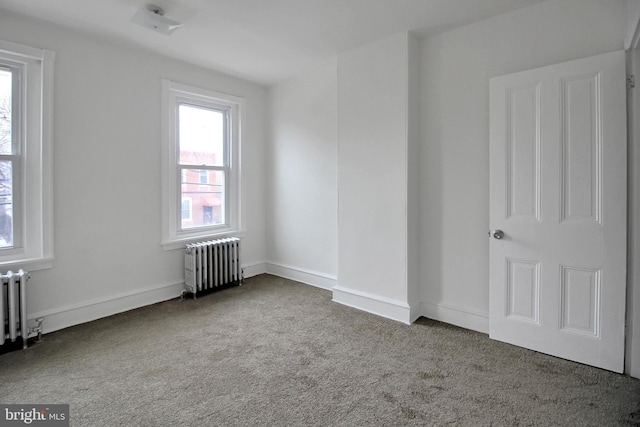 spare room featuring radiator heating unit and carpet flooring